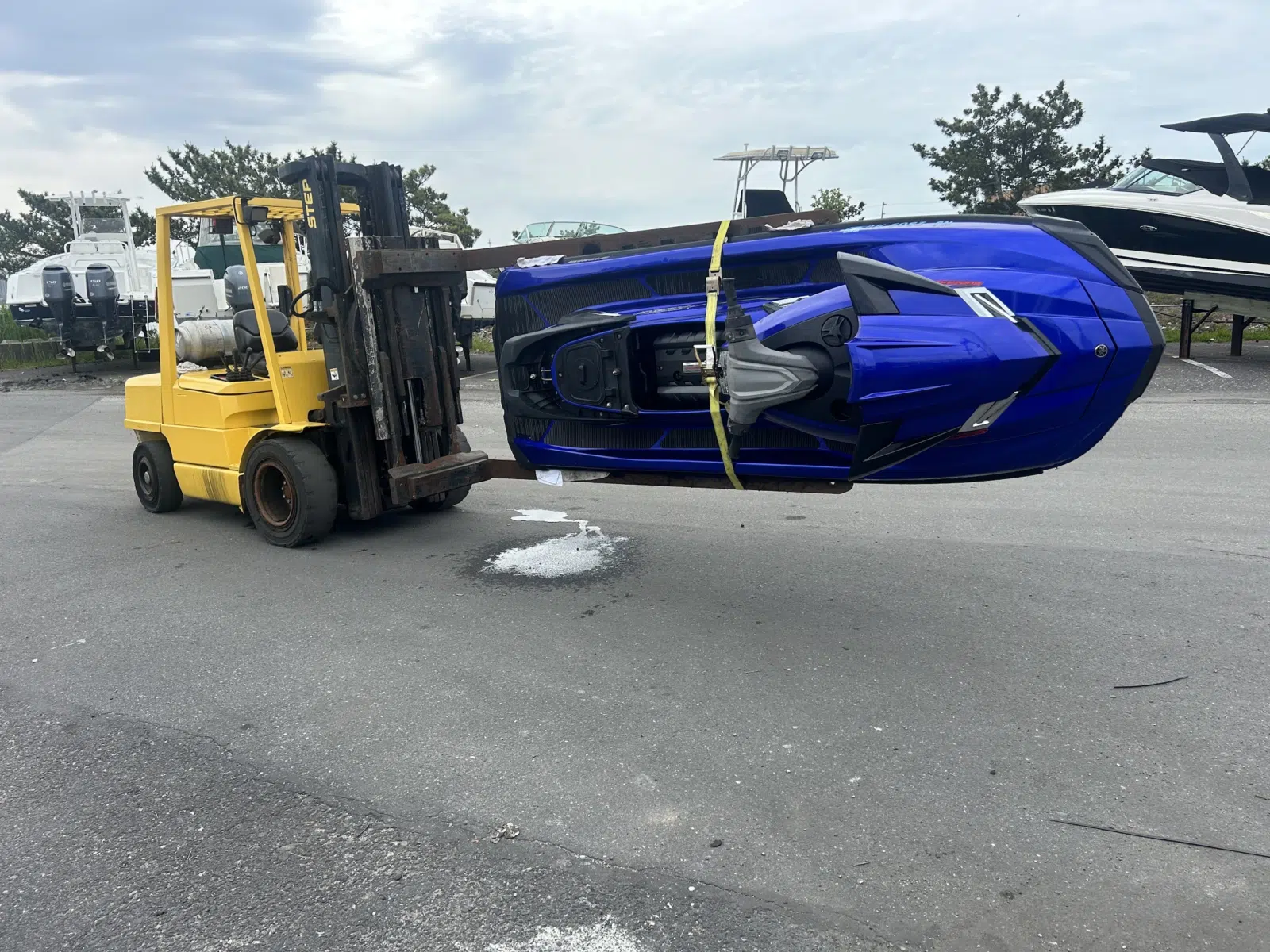 Blue jet ski lifted by a yellow forklift in the yard — JetPro Powersport in Atlantic City