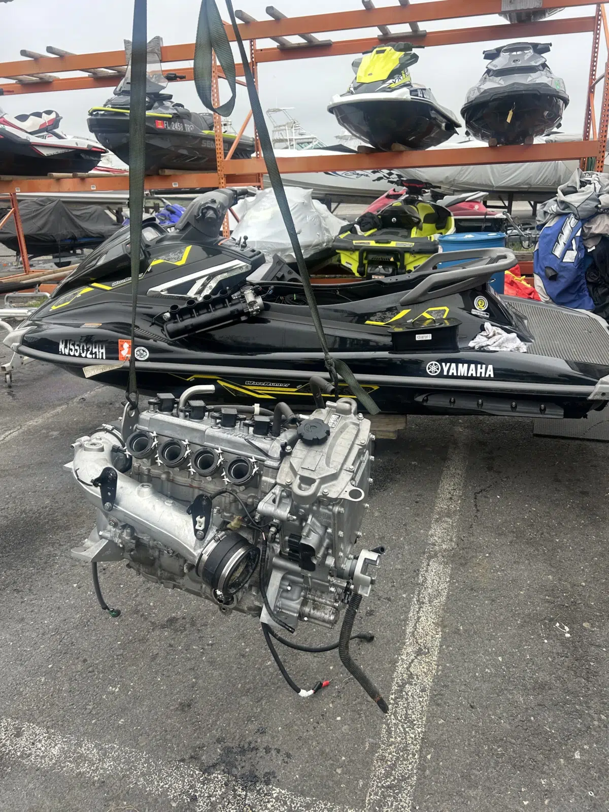 Yamaha engine hoisted by straps beside a black jet ski — JetPro Powersport in Atlantic City