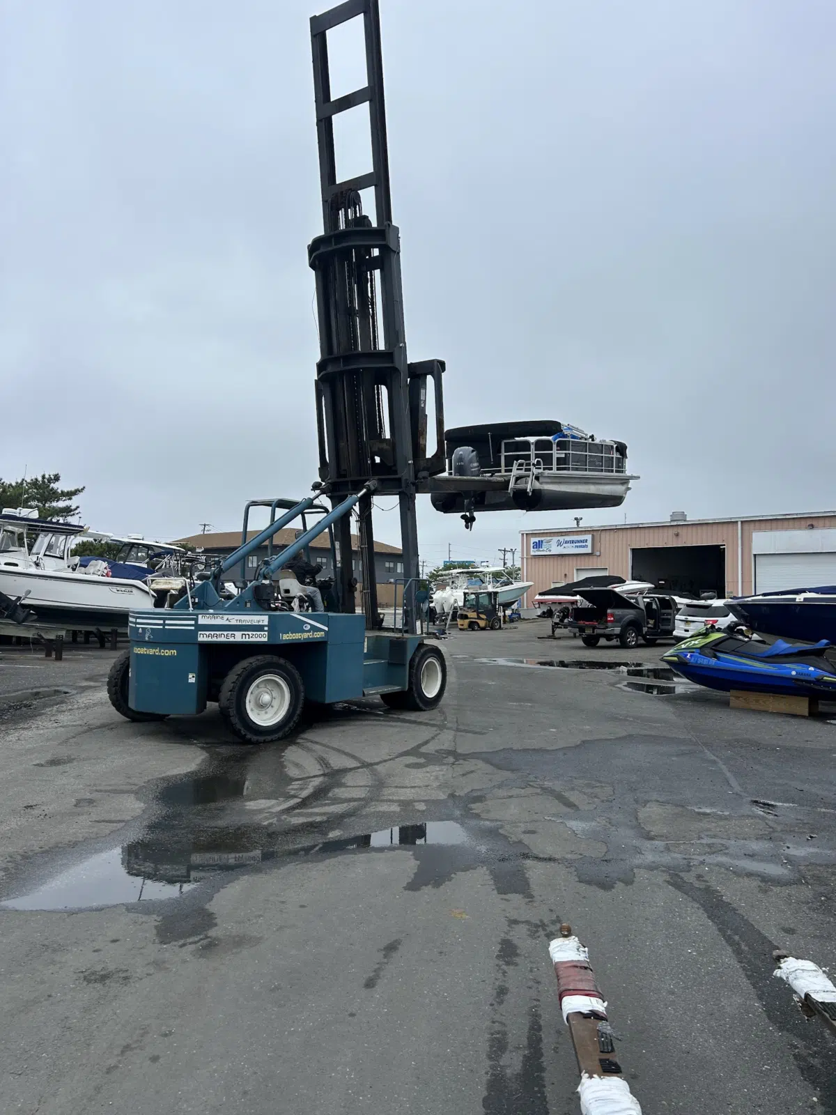 Marine forklift lifting a pontoon boat at the marina — JetPro Powersport in Atlantic City