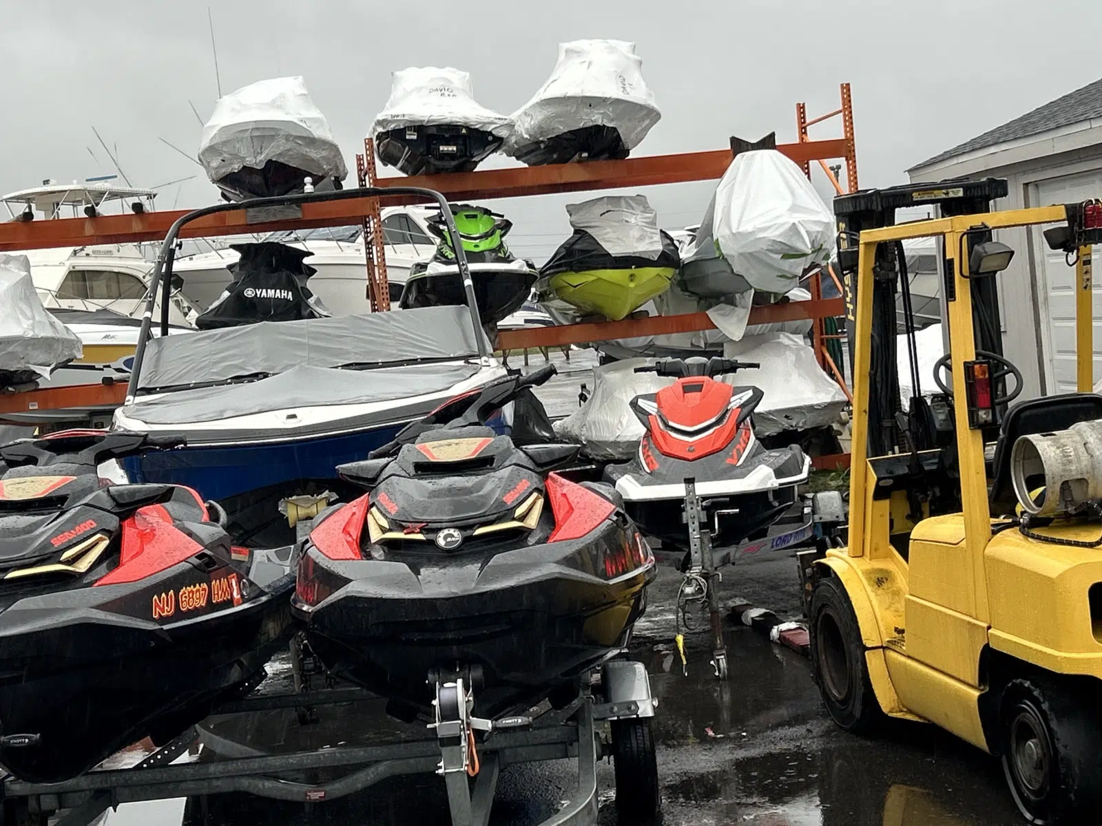 Covered jet skis stacked on racks beside a forklift — JetPro Powersport in Atlantic City